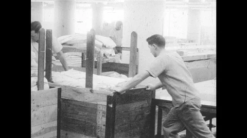1960s: Men push cart through factory. Women sew fabric. Stock Footage 98008559