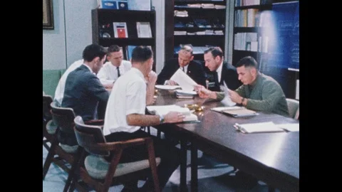1960s: Men seated around table. Astronauts in suits with men. Men putting Stock Footage 101666399
