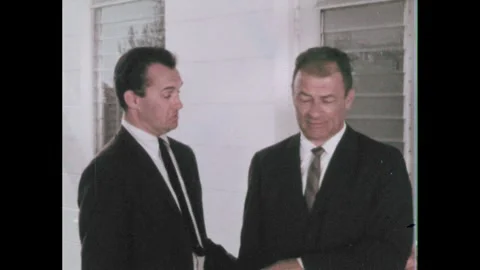 1960s: Men shake hands. Close up of woman talking. Man shrugs. Family walks from Stock Footage 253999425