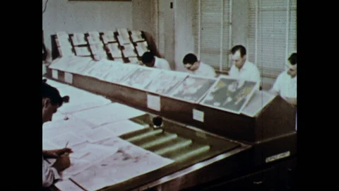 1960s: Men sit in rows at drafting tables drawing on weather maps. Man takes Stock Footage 126014077