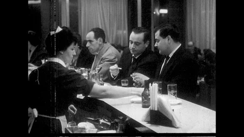 1960s: men smoking and drinking at bar, people sitting around tables in Video stock 129569736