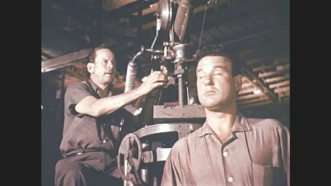 1960s: men work on sound boom microphone crane on movie soundstage. men talk and Stock Footage