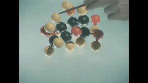 1960s: Model of cluster of molecules. Person points to areas of model. Stock Footage 258143591