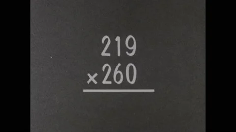 1960s: Multiplication problem appears. Hands shuffle math papers on desk. Boy Stock Footage 228701440
