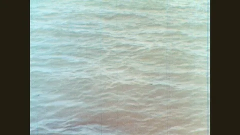 1960s: Ocean waves wash against rocks. Factory on shoreline. Water flows into Stock Footage