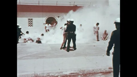 1960s: As one group of protesters flee the scene, another group trumps a car. Stock Footage