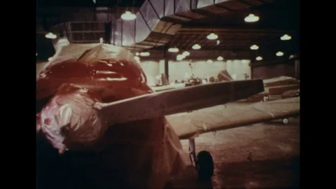 1960s: Pan of planes in hangar / Pan of crates of spray paint / Display of Stock Footage