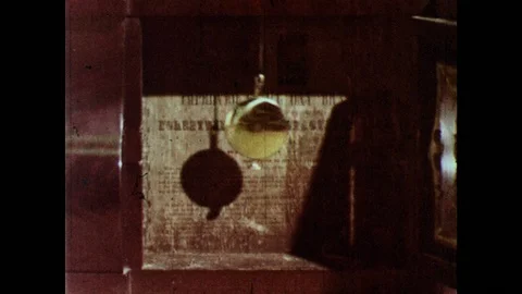 1960s: Pendulum on clock swings back and forth. Men launch model plane into air, Stock Footage 126012516
