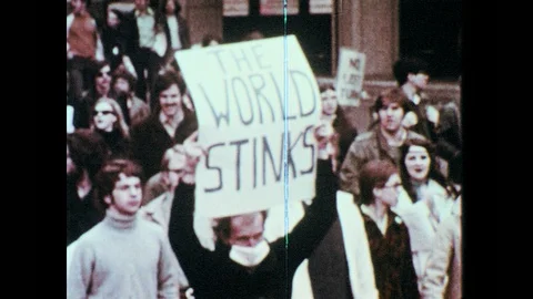 1960s: People march in street, carry signs, wear masks. Protest sign. Man speaks Stock Footage