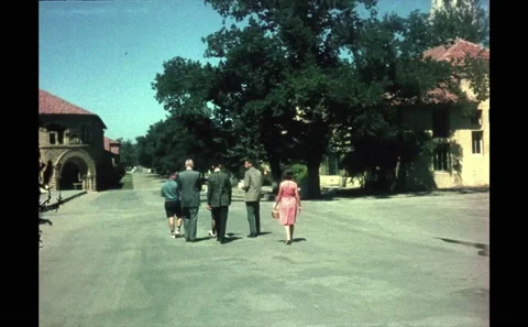 1960s: People walking down road together. Tower and building on Stanford Stock Footage