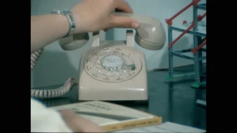 1960s: Phone on table, hand sets down receiver, hands open book, zoom out to boy Stock Footage 228835011