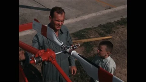 1960s: Pilot showing boy how tail rotor functions. Pilot showing boy parts of Video stock 219965541