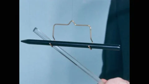 1960s: Probe hanging from string. Hands vigorously rubbing with cloth. Probe Stock Footage 166466660