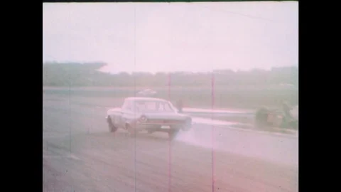 1960s: Race car speeds down pit road. Spectators stand. Cars drive down track. Stock Footage