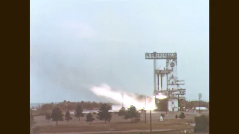 1960s: Rocket booster engine fires from launch pad. Men work on rocket booster. Stock Footage 77051898