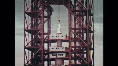 1960s: Rocket in launch position. Elevator moves up to top of rocket 動画素材 77449003