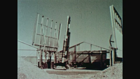 1960s: Rocket sits on launch pad in middle of building facility. Rocket on Vídeos de archivo 124817347
