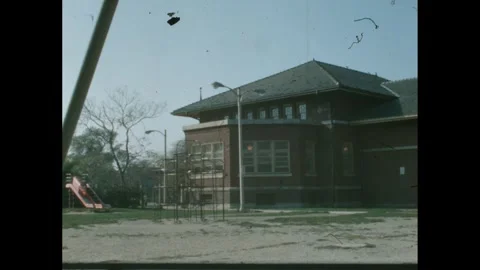 1960s: Sad looking playground behind the school, swings swaying in the breeze. Stock Footage 275857690