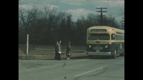 1960s: School bus pulls over, people get ready to board. Two people stack their Stock Footage 243928376