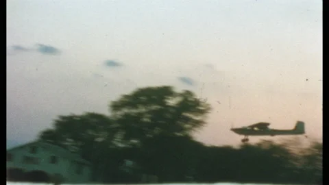 1960s: Small plane lands on grass field. Airplane in the sky with parachuter. Stock Footage 132612092