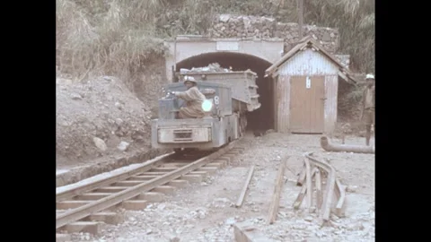 1960s: Small train passes through tunnel.  Man drives train.  Workers walk. Stock Footage 287214618