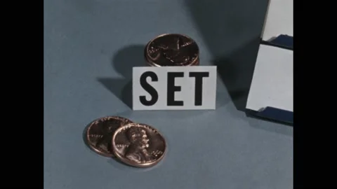 1960s: Stack of pennies by label, hand sets down penny. Number cards on stands. Stock Footage 169593990