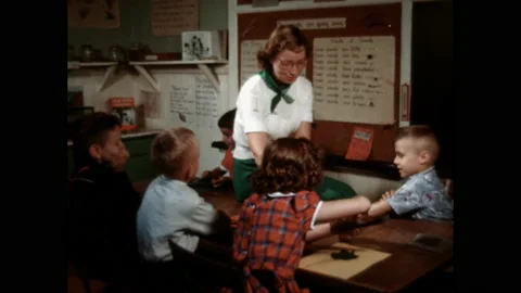 1960s: Student sit around table, teacher sits on table. Teacher shows students Stock Footage 142927672