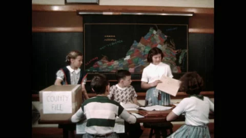 1960s: Students sit at table, work. Girl points to map, talks. Girl hands 库存影片 142926596