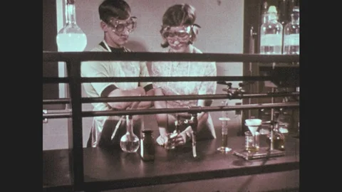 1960s: Students work at laboratory table. Boy and girl look at each other. Stock Footage