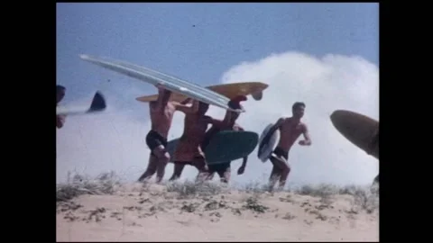 1960s Surfing, running across sand hills with their surfboards. Stock Footage