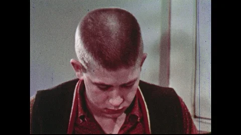 1960s: Teenage boy nods head. Man sits behind desk, ruffles through papers, has Stock Footage