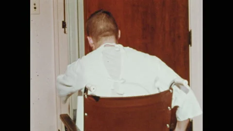 1960s: Teenage boy in wheelchair talks to man on bed in hospital room. Boy Stock Footage