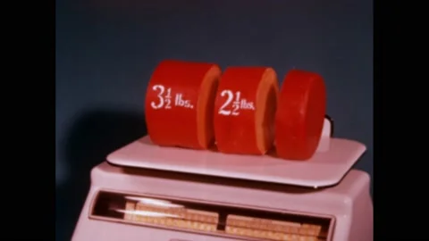 1960s: Three, red, cylinder objects sit on scale, two are labeled with different Stock Footage 169592397