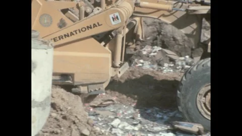 1960s: Trailer pulled by truck, dumps dirt over garbage in landfill. Stock Footage 244535691