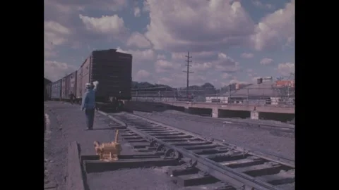 1960s: Train moving in rail yard, men working by tracks. Stock Footage 277674956