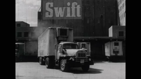 1960s: Train rolls down tracks. Commercial trailer truck pulls away from loading Stock Footage 231419634