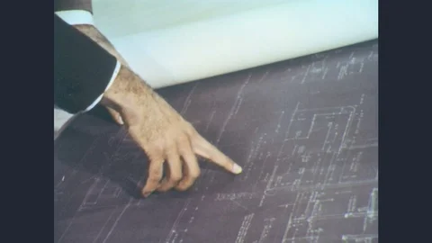 1960s: Two men at drafting table review blueprints. One man pints to a specific Stock Footage 77105423