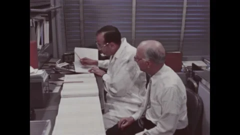 1960s: Two men in lab examine polygraph results, man opens book to check Vídeos de archivo 212809139