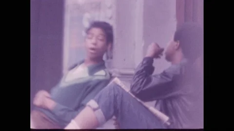 1960s: Two men sit lethargically against a wall. The two talk. One rubs his Vidéo 220240792