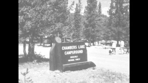 1960s: UNITED STATES: Chambers Lake Campground sign. Cars parked by hotels and Stock Footage