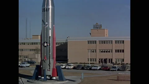 1960s: USAF rocket mounted outside of building and parking lot, people walking Vídeos de archivo 151061694