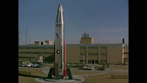 1960s: USAF rocket mounted outside of building and parking lot, people walking Vídeos de archivo 151061774