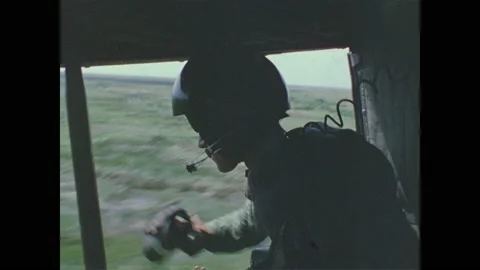 1960s Vietnam: Gunner tosses smoke grenades from open door on helicopter. Gunner Stock Footage