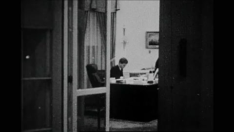 1960s: View through window, John F Kennedy in Oval Office, zoom out. Pan of car Stock Footage 167371107