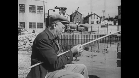 1960s: Waterfront.  Boy speaks to man fishing.  Man works on fishing rod.  Boy Stock Footage 295371978