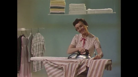 1960s: Woman irons shirt in laundry room. Stock Footage