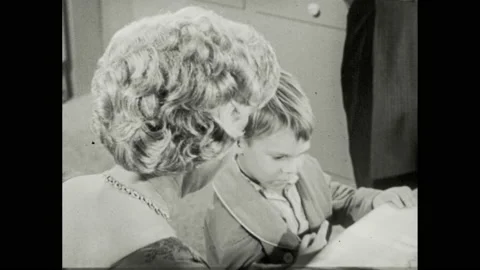 1960s: Woman talks to boy at kitchen table who dips finger into cake frosting. Stock Footage