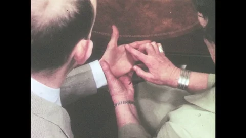 1960s: Woman's hand traces letters on the palm of a man's hand. Stock Footage