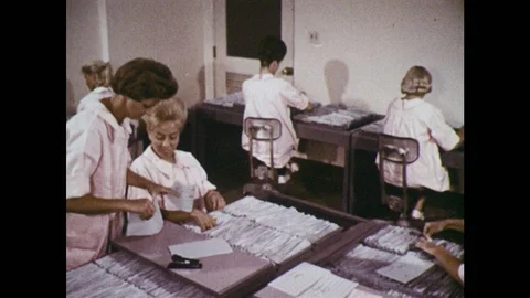 1960s: Women file papers in office setting. Women carry computer tape reels in Stock Footage