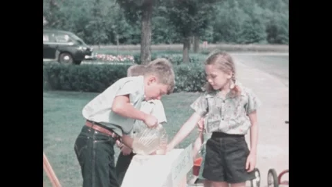 1960s: Yard.  Children approach boy at lemonade stand.  Little boy pours.  Girl Stock Footage 254366235